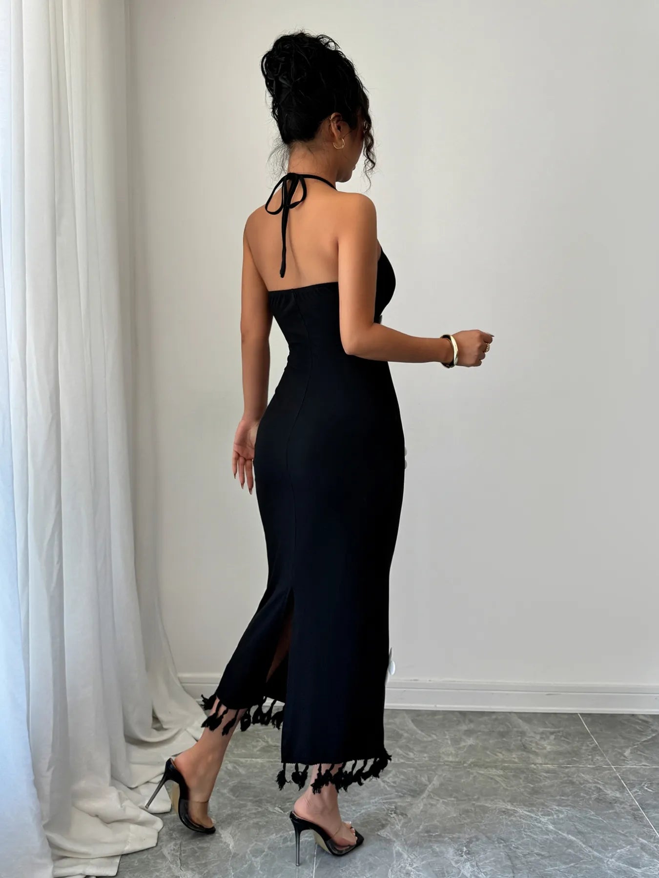 Woman wearing a black dress with white trim in a minimal indoor setting