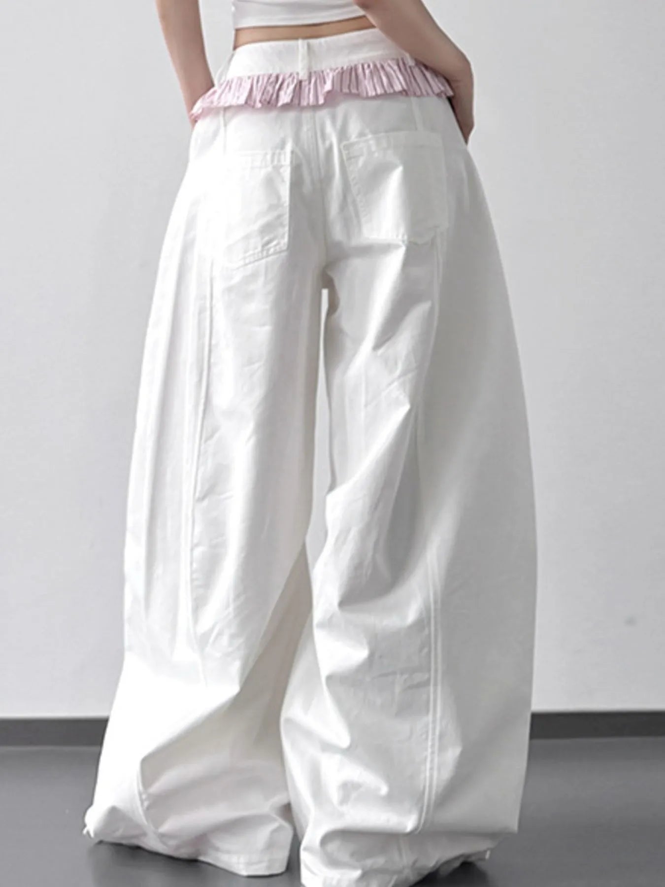 White wide-leg pants with a pink waistband on a plain background