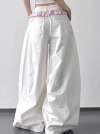 White wide-leg pants with a pink waistband on a plain background