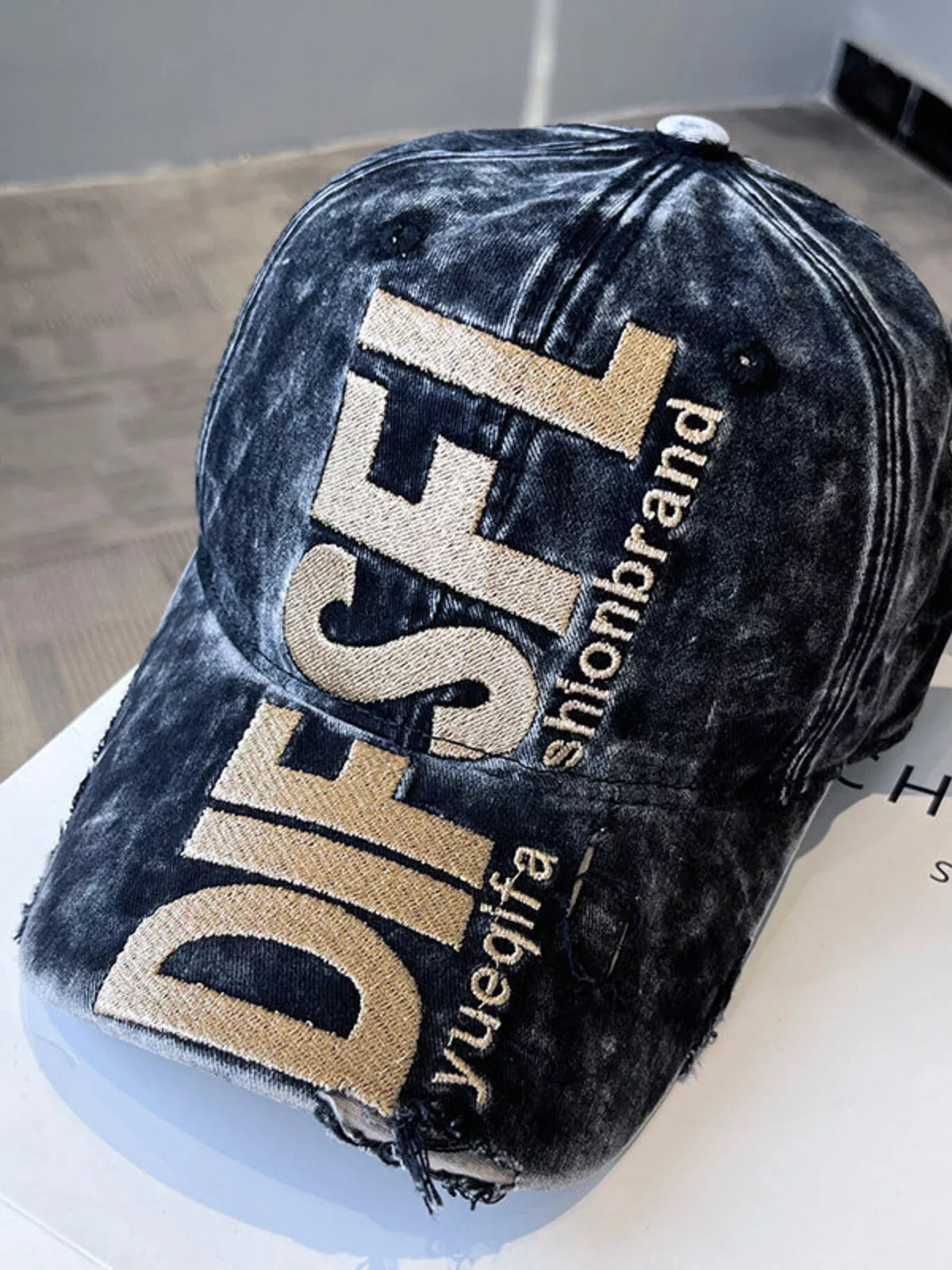 Blue distressed cap with 'DIESEL' branding on a light surface
