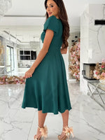 Woman wearing a teal dress in a modern interior setting