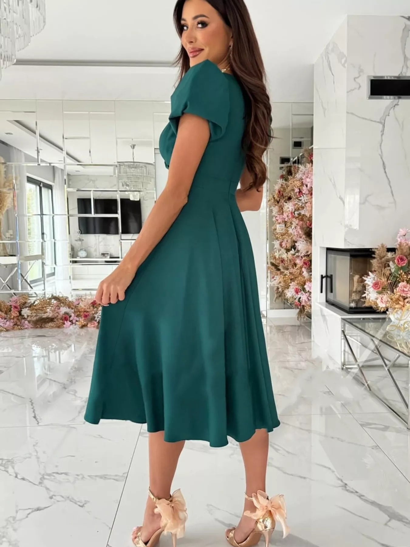 Woman wearing a teal dress in a modern interior setting