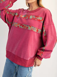 Pink sweatshirt with floral patterns on a plain background