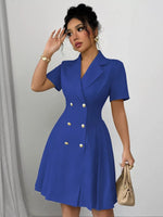Woman wearing a blue dress with gold buttons against a plain background