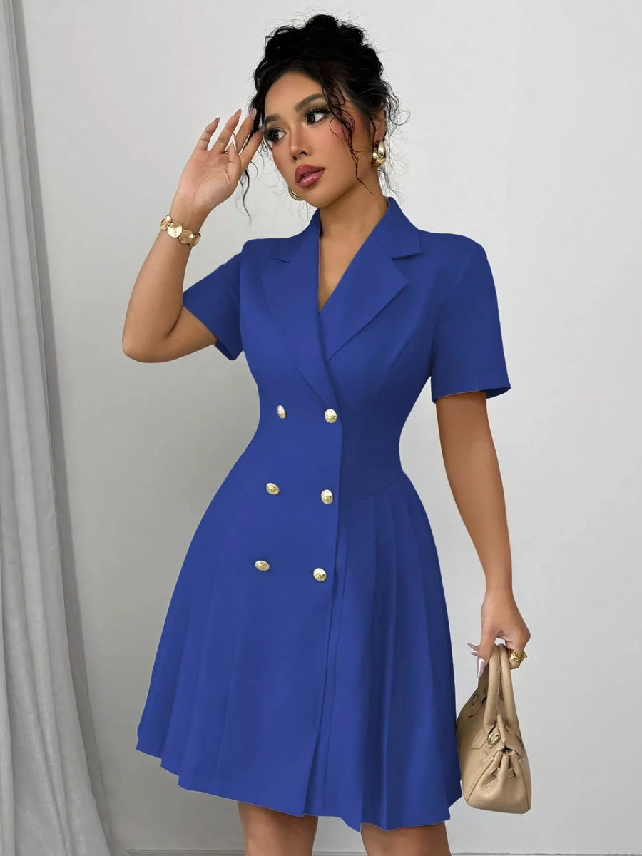 Woman wearing a blue dress with gold buttons against a plain background