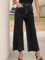 Person wearing black wide-leg jeans outdoors on a concrete surface.