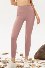 Person wearing pink leggings standing on a natural ground with rocks and leaves.