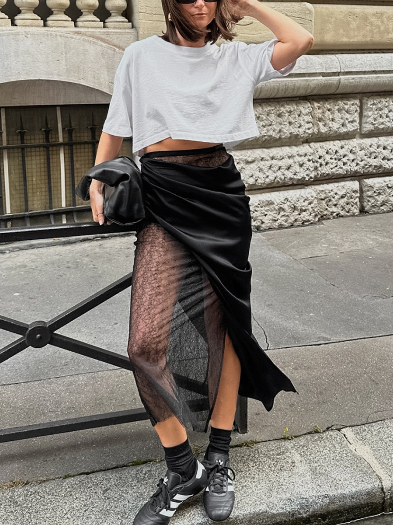Person wearing a white crop top and black sheer skirt on a city street.