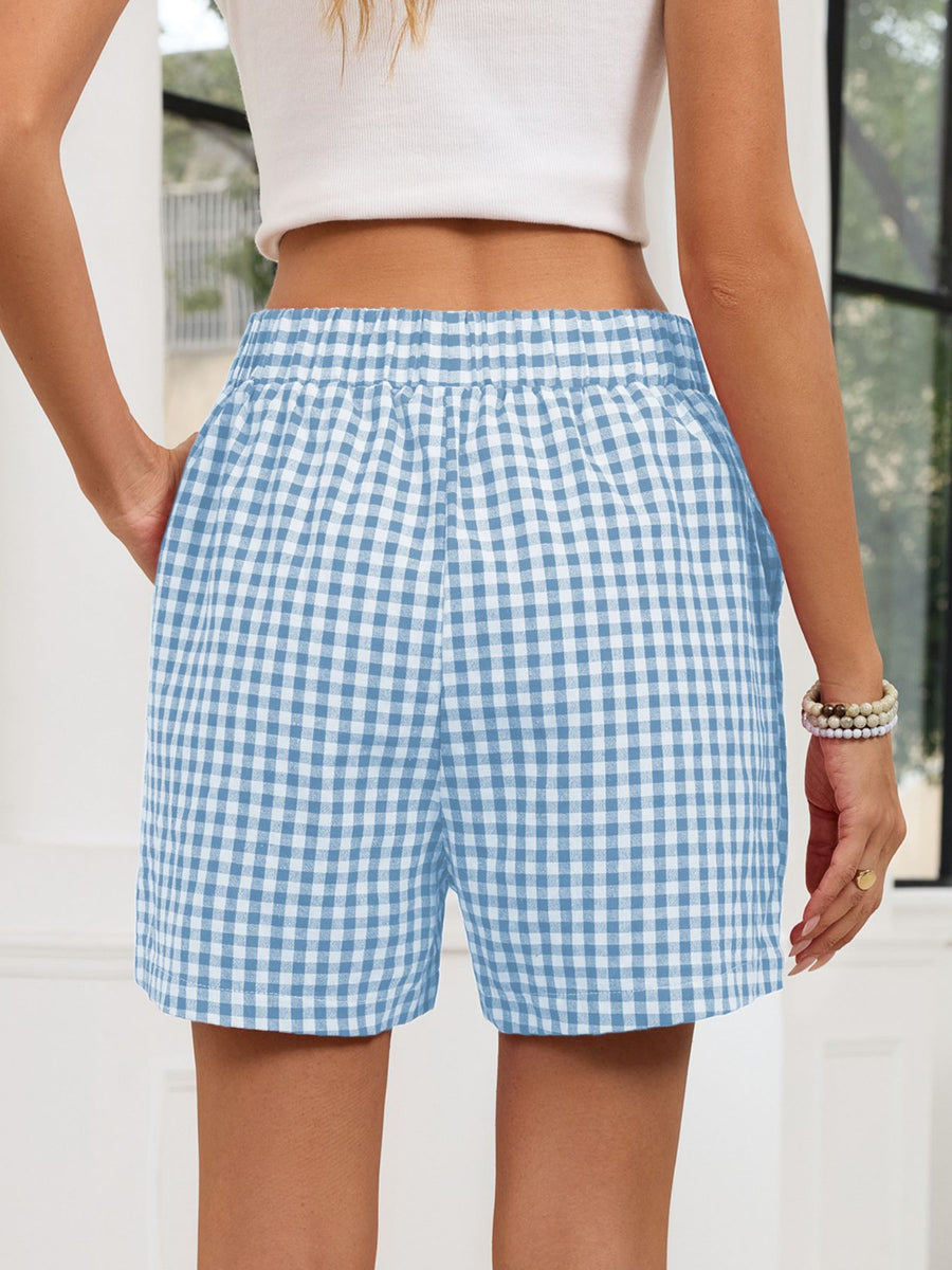 Person wearing blue and white checkered shorts with a blurred background