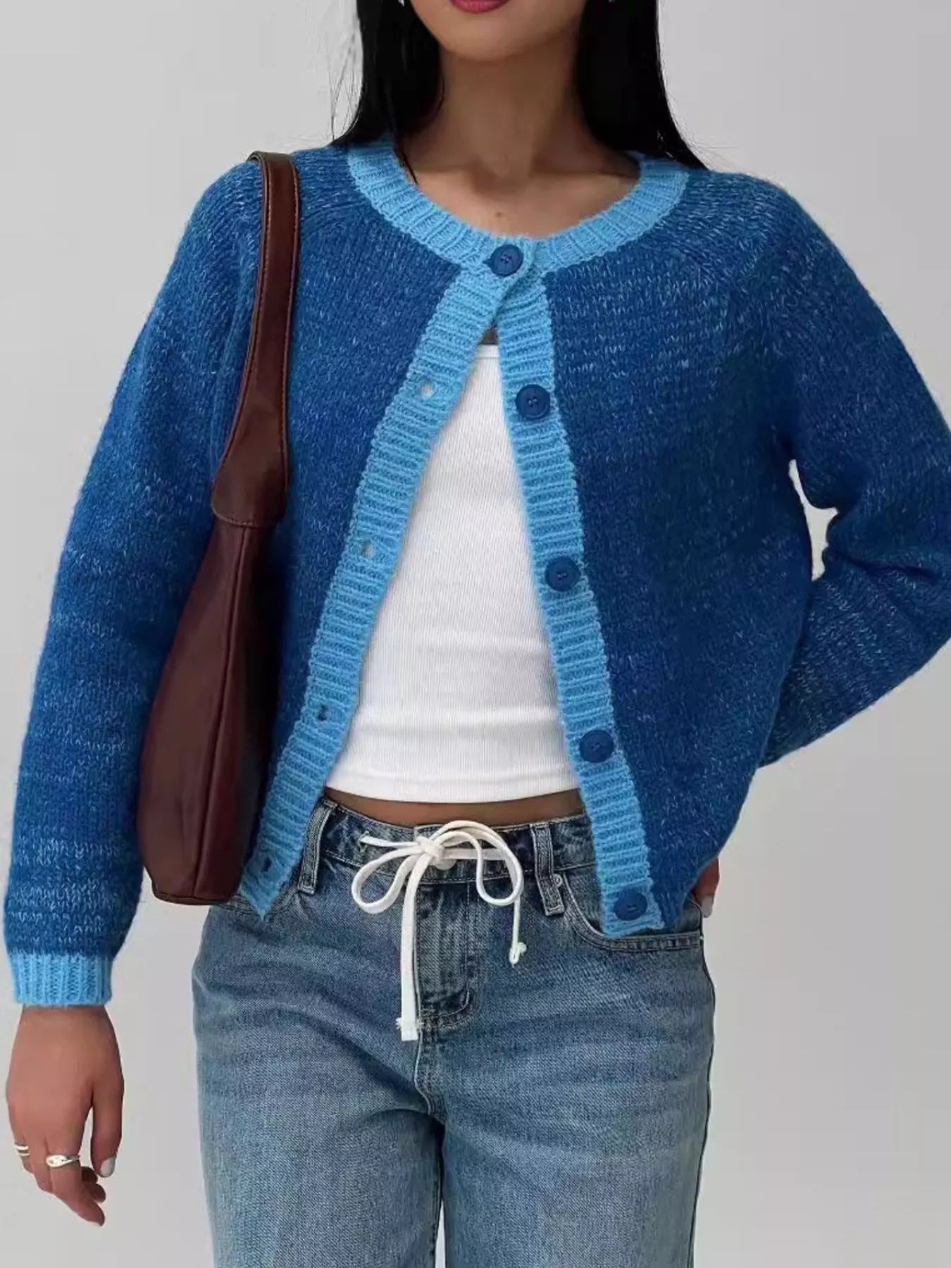 Person wearing a blue knitted cardigan with a plain background