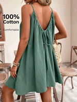 Woman wearing a green dress with an open back in a room with wooden furniture.
