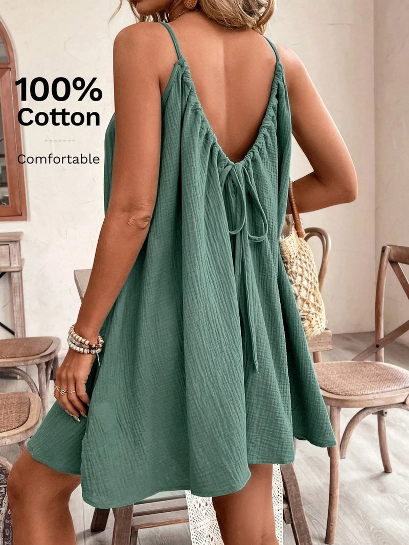 Woman wearing a green dress with an open back in a room with wooden furniture.