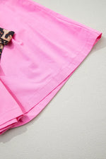 Pink fabric with a leopard print trim on a light gray background