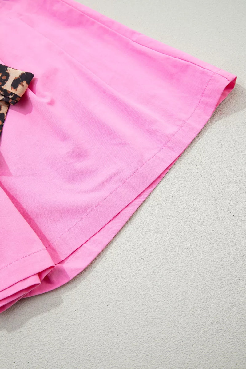 Pink fabric with a leopard print trim on a light gray background