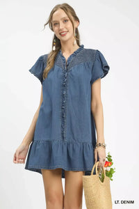 Woman wearing a light denim dress holding a basket with flowers on a white background