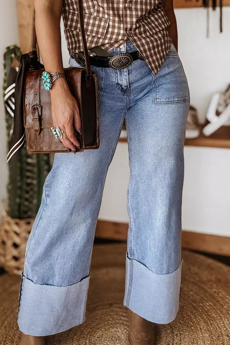 Person wearing rolled-up light blue jeans with a plaid shirt and brown leather bag.