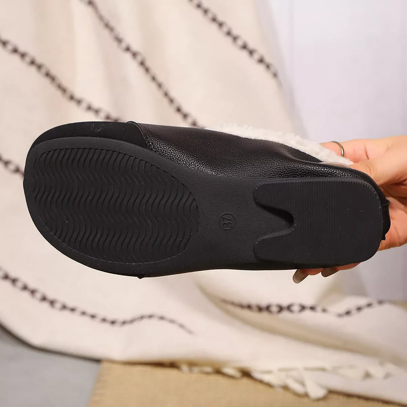 Black shoe sole held by a hand with a patterned fabric background