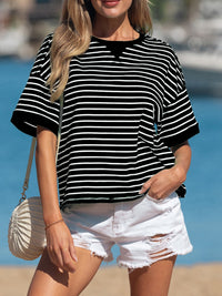 Woman wearing a black and white striped shirt and white shorts with a beach background