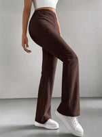 Person wearing brown ribbed pants and white sneakers on a plain background