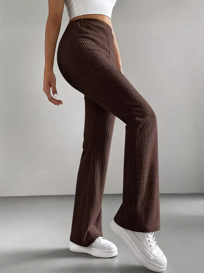Person wearing brown ribbed pants and white sneakers on a plain background