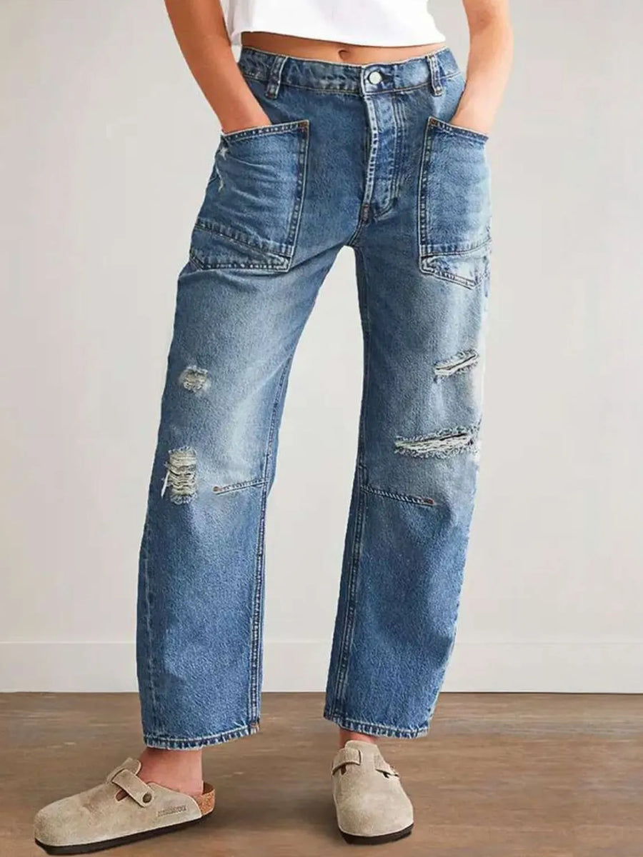 Person wearing distressed blue jeans with a plain background