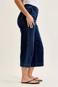 Person wearing dark blue wide-leg jeans on a plain background