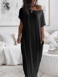 Woman wearing a black off-shoulder dress in a minimalistic room.