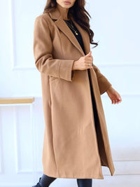 Woman wearing a long beige coat against a white background