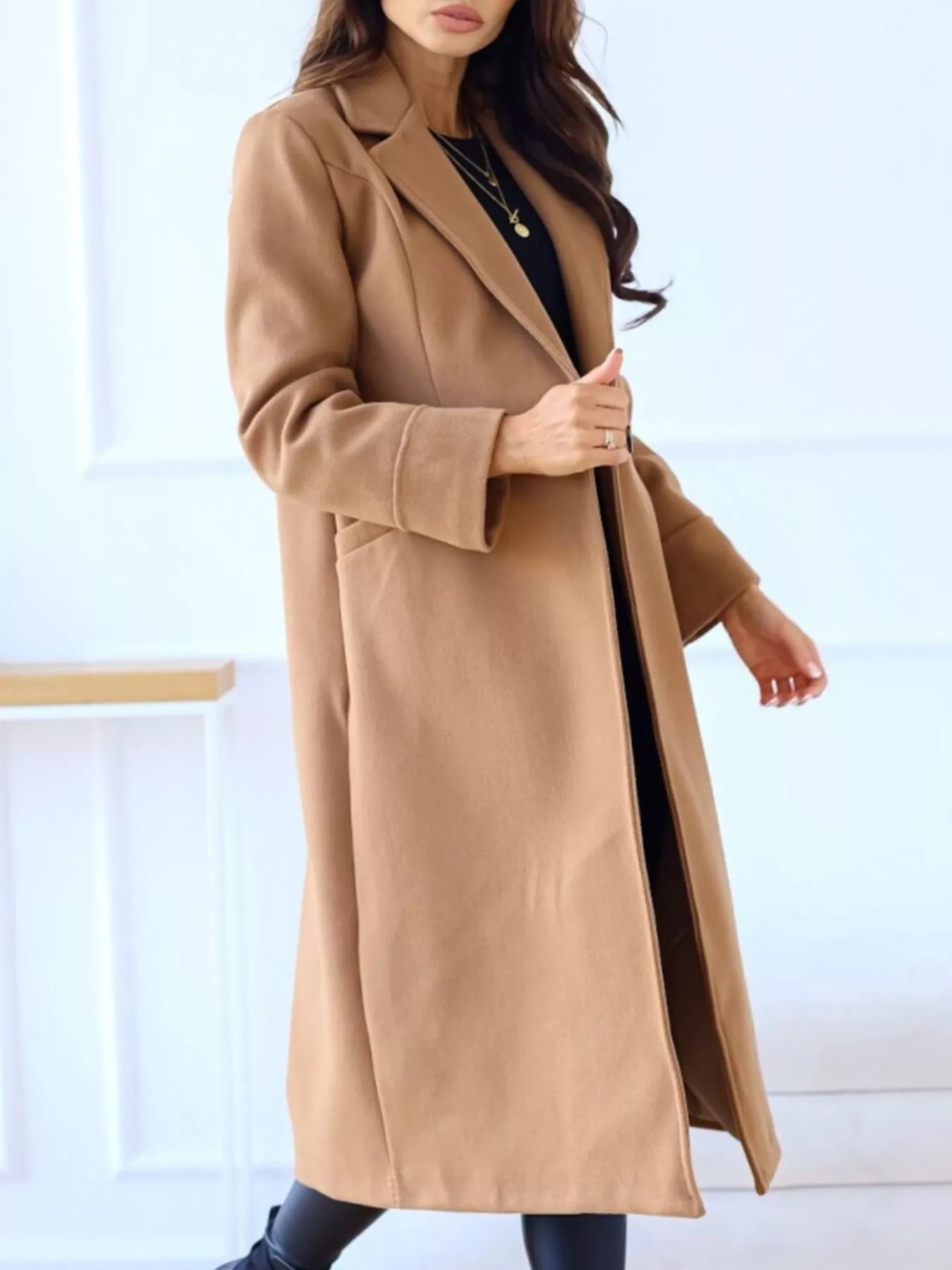Woman wearing a long beige coat against a white background