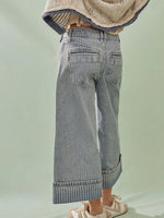 Person wearing light blue jeans with a plain background