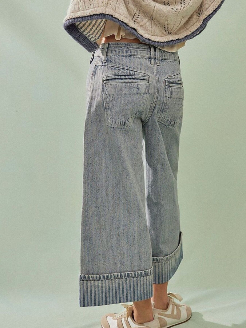 Person wearing light blue jeans with a plain background