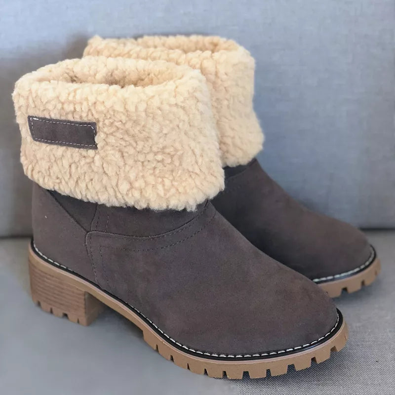 Pair of gray winter boots with beige fleece lining on a light blue background