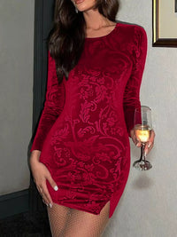 Woman wearing a red velvet dress holding a glass of wine indoors.