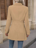 Person wearing a beige coat standing on a street.