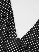 Close-up of a black polka dot fabric with a white background