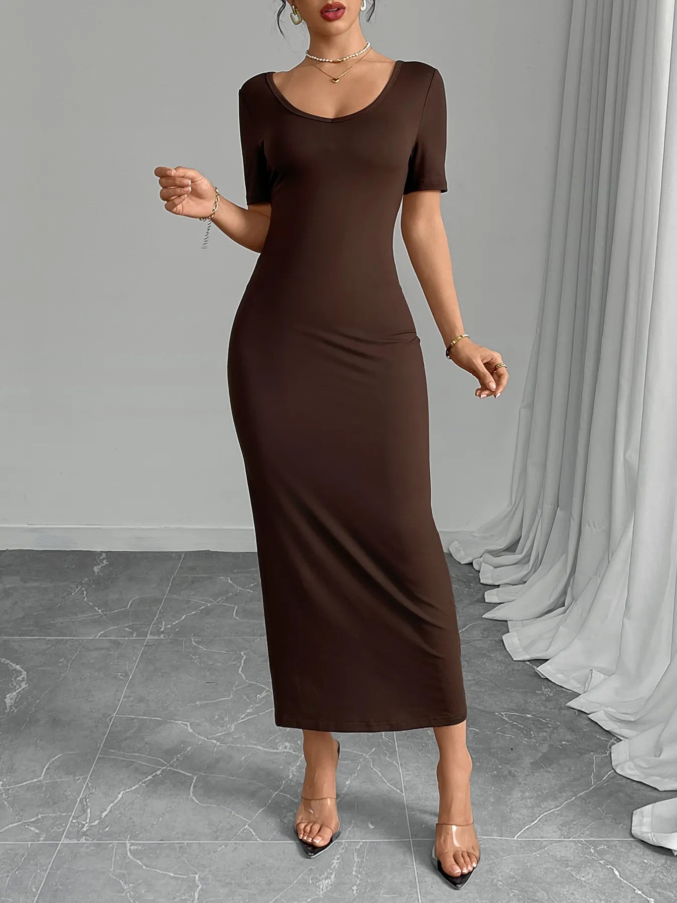 Woman wearing a brown dress standing against a gray background