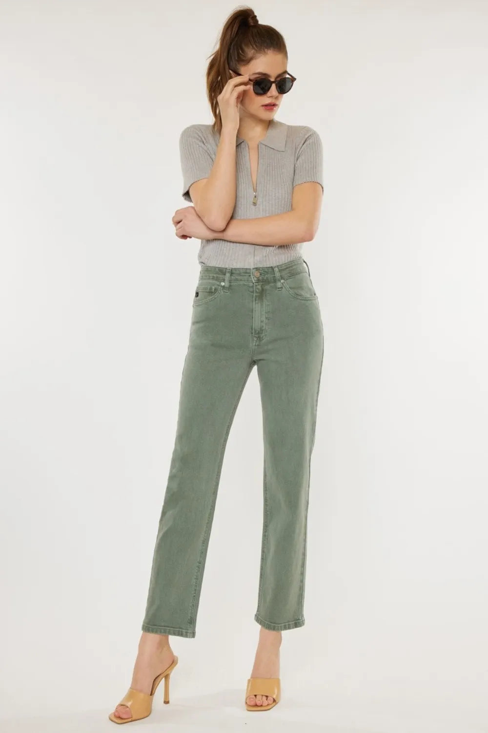 Woman wearing a gray top and green pants on a white background