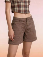 Person wearing brown shorts and a plaid shirt on a gradient background