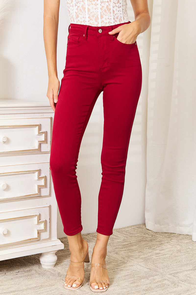 Red pants worn by a person in a room with a white dresser and light-colored carpet.