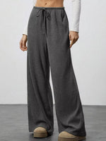 Person wearing gray wide-leg pants on a plain background