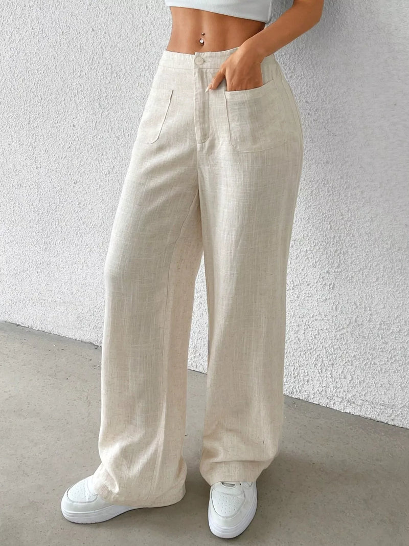 Person wearing beige wide-leg pants and white sneakers against a light gray background