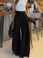 Person wearing a white top and black wide-leg pants in a cafe setting