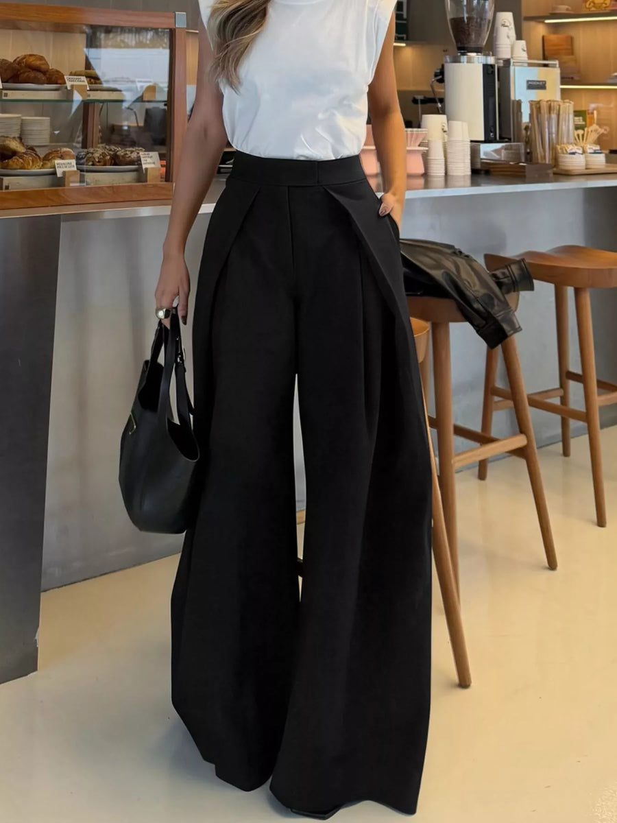 Person wearing a white top and black wide-leg pants in a cafe setting