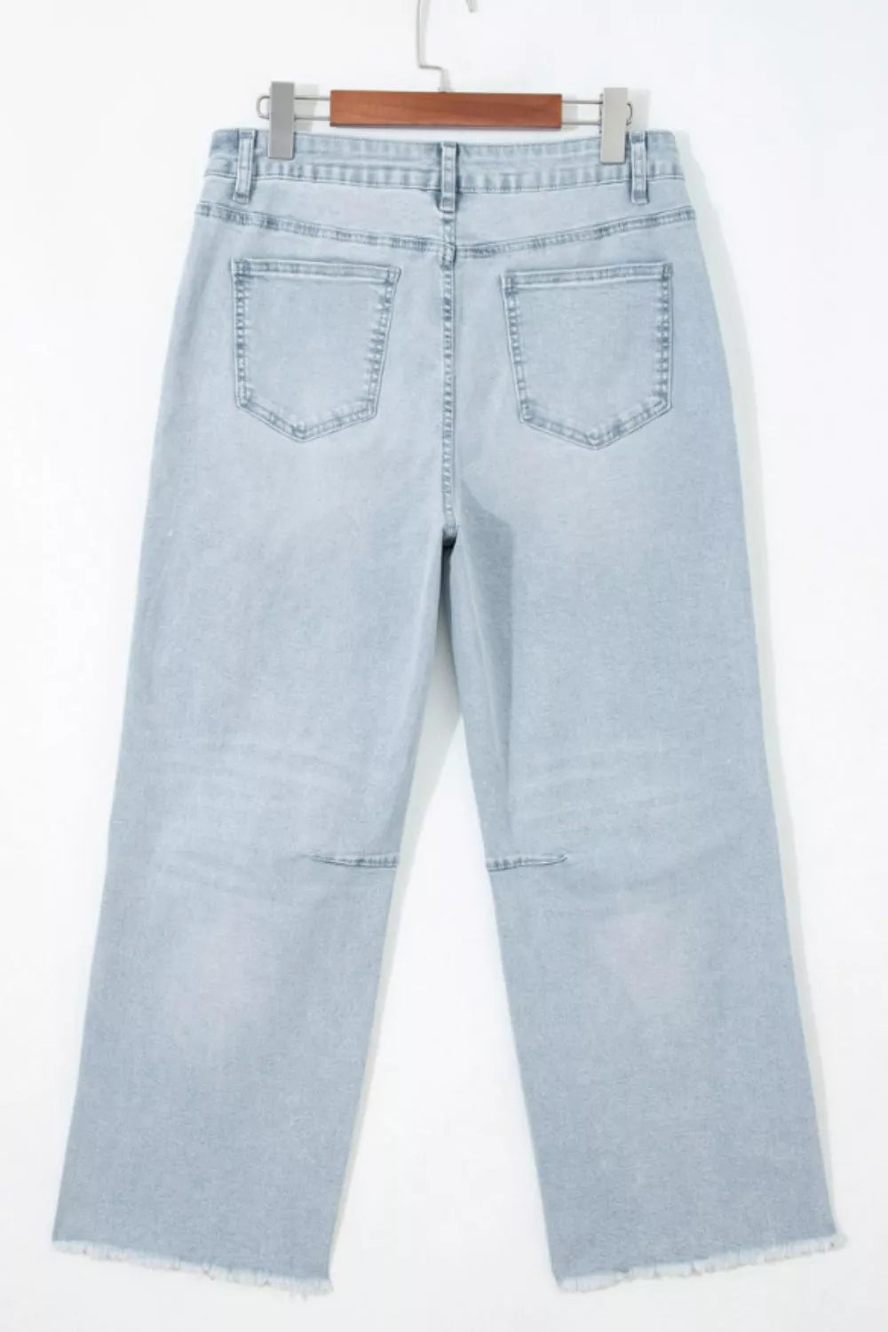 Light blue jeans hanging on a white background