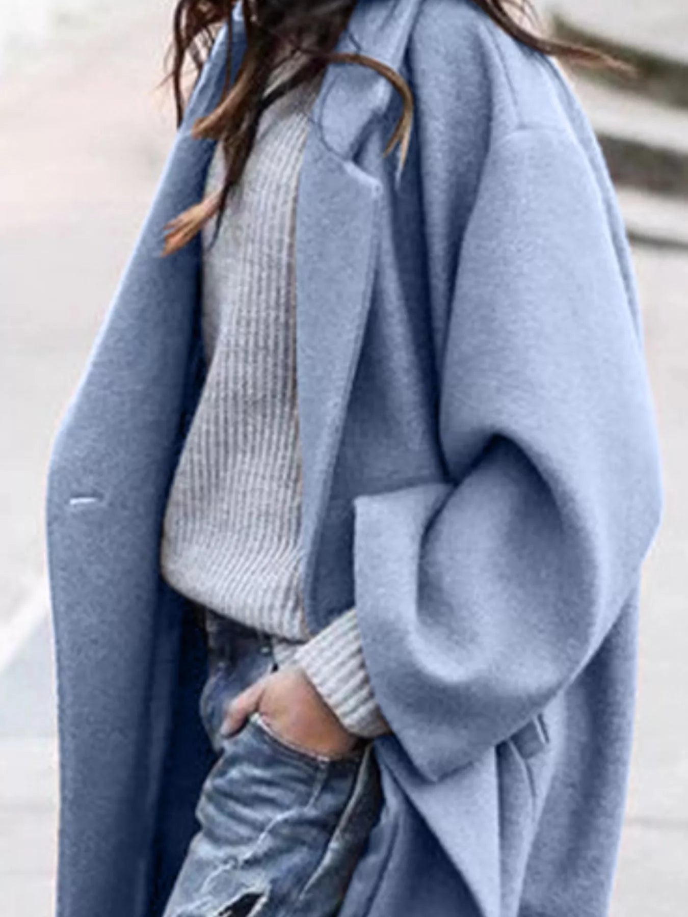 Person wearing a light blue coat over a gray sweater and jeans.