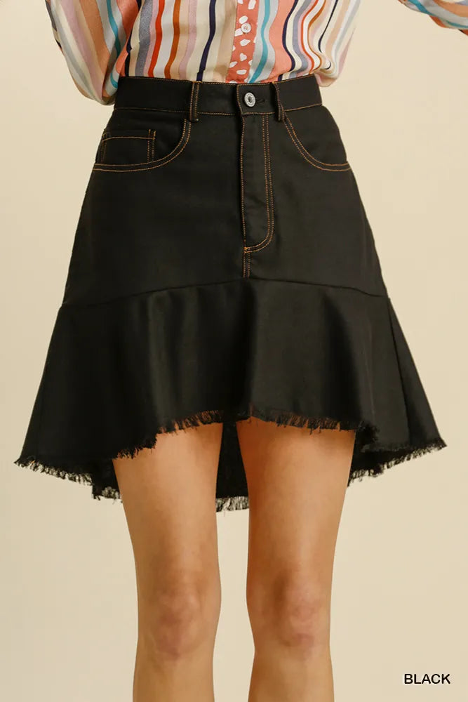 Black denim skirt worn by a person on a beige background