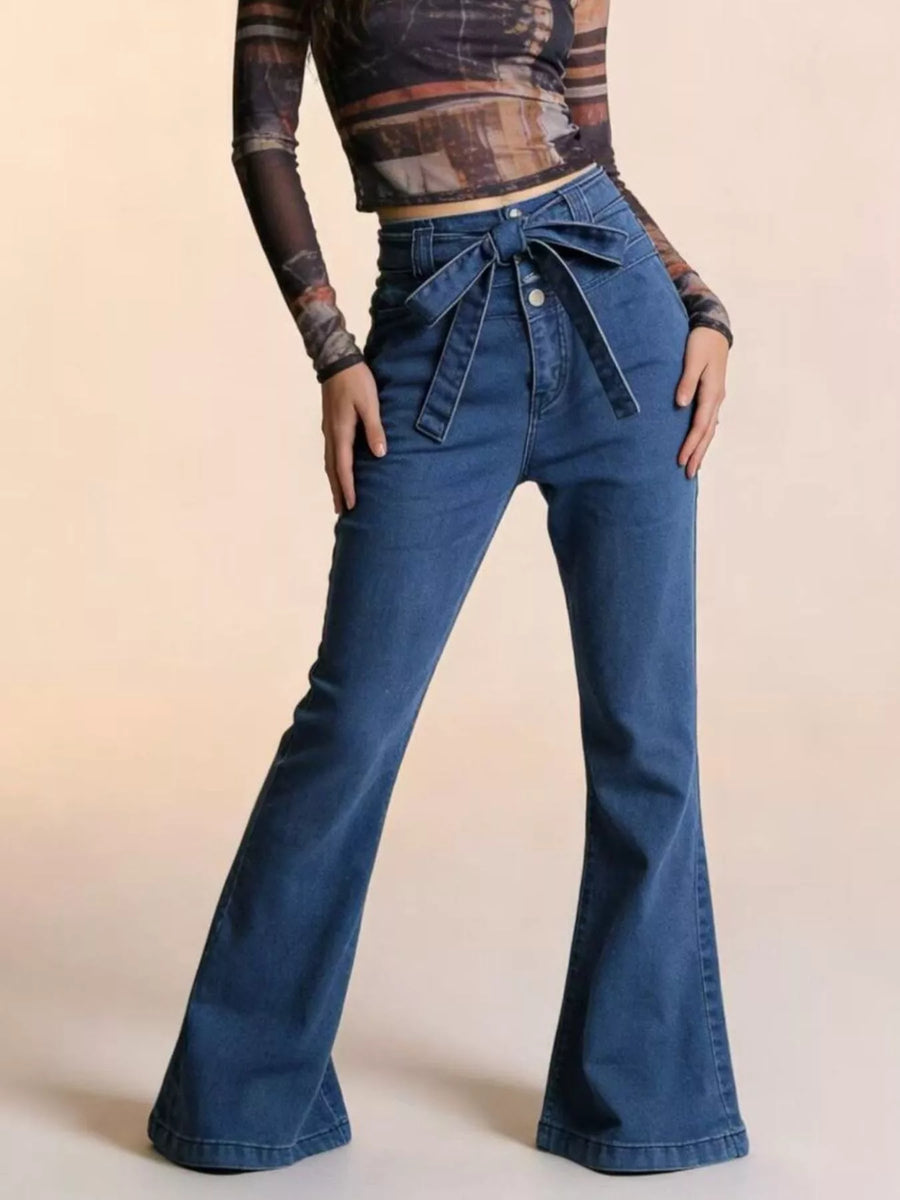 Person wearing blue flared jeans on a beige background