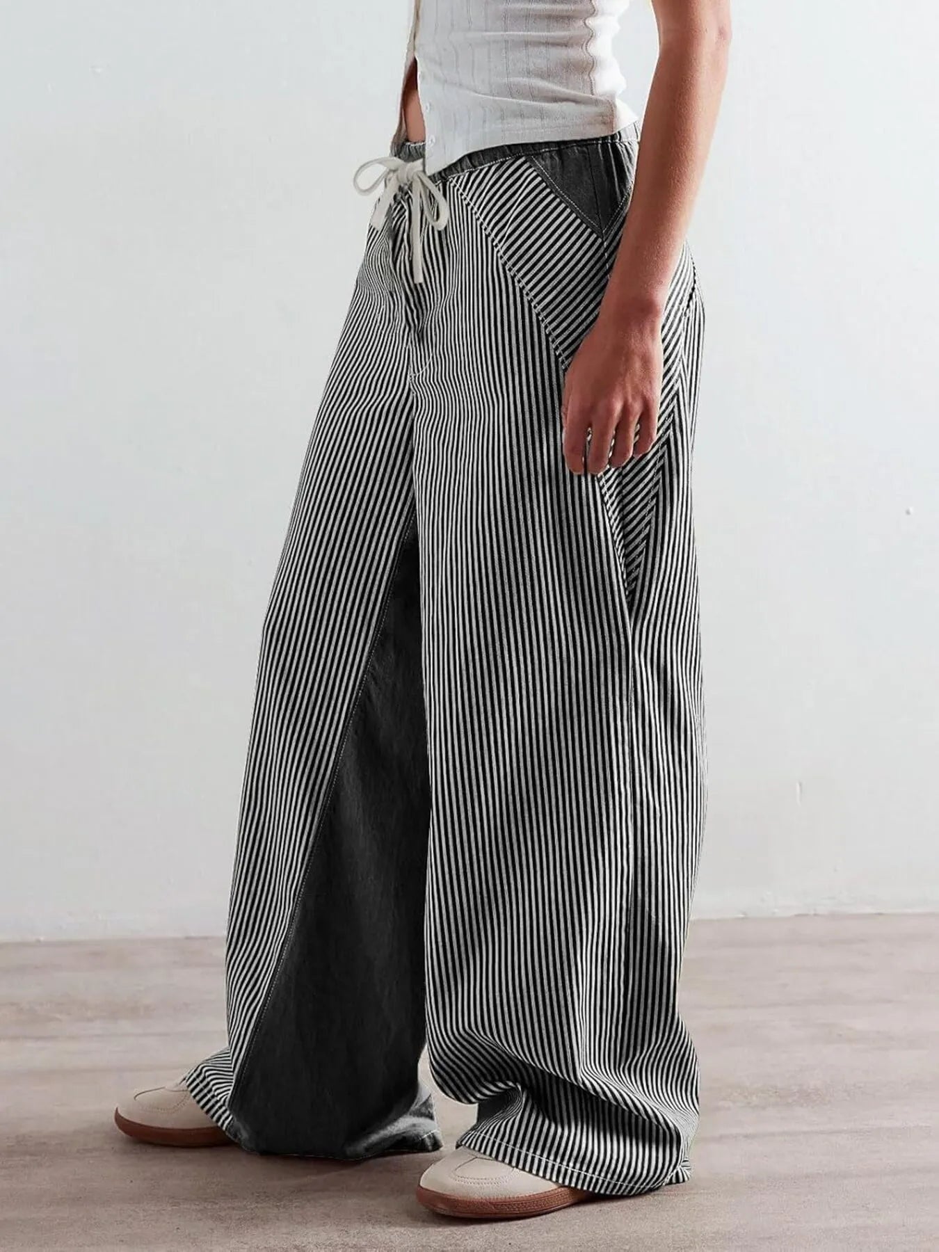 Person wearing black and white striped wide-leg pants on a plain background