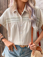 Person wearing a white lace-trimmed shirt with denim shorts and a brown handbag.