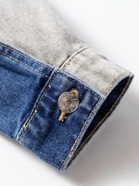 Close-up of a button on a denim jacket with a gray fabric background
